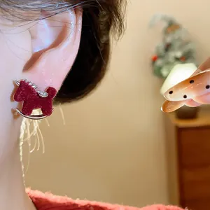 Detail view of a retro red flocked rocking horse earring with silver needle on ear