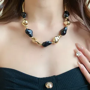 Dettaglio di un'elegante collana vintage con perle irregolari in nero e oro lucido