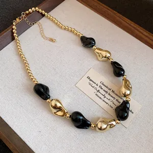Primo piano di perline geometriche irregolari nere e oro su una collana in stile vintage