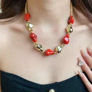 Vista dettagliata di una collana di perle rosse e dorate irregolari in stile vintage su modella