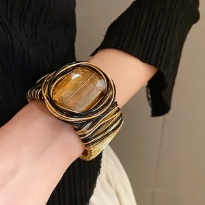 Bracciale bohémien intrecciato oro e nero con grande pietra di vetro ambrata quadrata