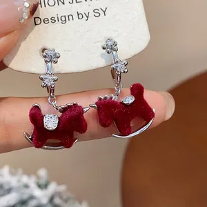 Close-up of red flocked rocking horse earrings with sparkling zircon flower studs.