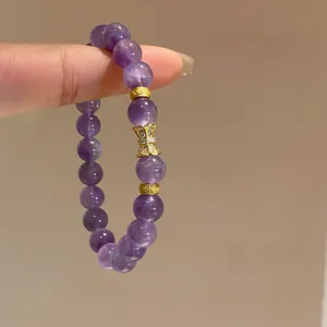 Close-up of elegant purple amethyst beaded bracelet with gold butterfly charm.