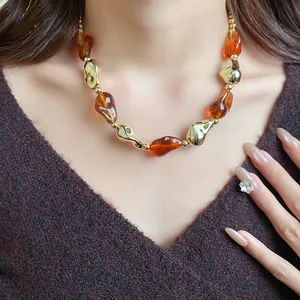 Collana vintage con perle in acrilico ambra e oro indossata su maglione a V