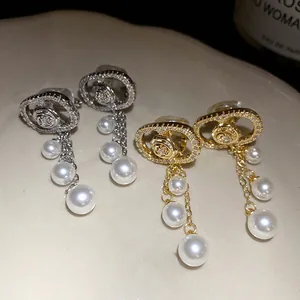 Close-up detail of elegant 18k gold and silver plated earrings with dangling pearls.
