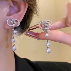 Close-up of elegant zirconia oval clip-on earrings with pearl tassels shown on ear.
