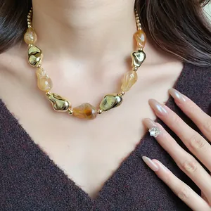 Primo piano dettagliato di una collana vintage in acrilico con perle ambra e oro.