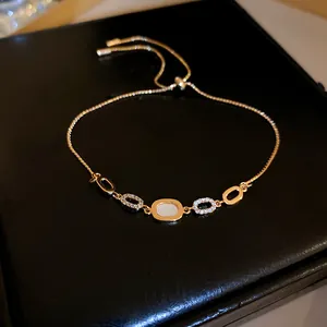 Elegant gold-tone bracelet featuring geometric oval charms with zircon and shell inlay.