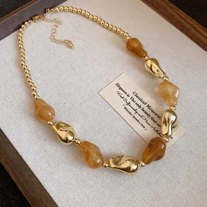 Primo piano di collana vintage con perle d'ambra irregolari e grani dorati