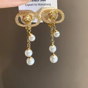 Detailed macro view of 18k gold plated oval earrings with pearl tassels and CZ accents.