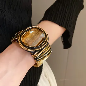 Dettaglio ravvicinato di un bracciale a polsino intrecciato con vetro quadrato