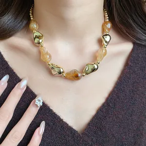 Elegante primo piano di una collana con perle geometriche ambra e oro su modella