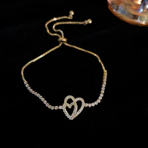 Detailed close-up of a gold-plated adjustable bracelet featuring pavé-set double hearts.