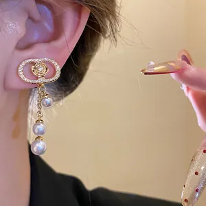 Detail shot of 18k gold plated oval zircon earrings with elegant pearl tassels on ear.