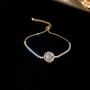 Detailed close-up of adjustable gold-toned tennis bracelet with sparkling central zircon