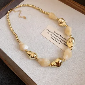 Dettaglio di una collana vintage con perle acriliche irregolari su vassoio lino