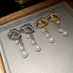 Detail view of 18k gold plated oval zircon earrings with hanging pearl tassels