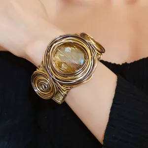 Vista dettagliata del bracciale rigido intrecciato boho con grande vetro giallo