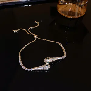 Close-up of golden snake-head bracelet encrusted with emerald green and clear zircons.