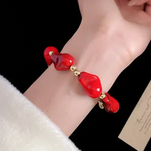 Dettaglio di un bracciale vintage in perle acriliche rosse con inserti dorati lucidi