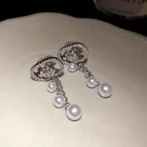 Close-up of 18k gold plated oval pearl tassel ear clips with sparkling zircon stones
