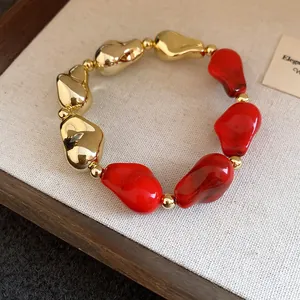Primo piano di un braccialetto vintage con perline irregolari rosse e dorate lucide.