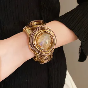 Dettaglio di bracciale rigido boho in filo metallico con vetro ambrato