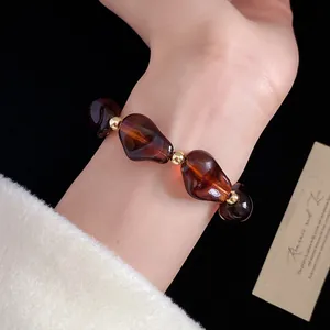 Dettaglio ravvicinato di bracciale vintage con perline acriliche irregolari al polso.