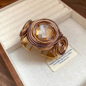 Dettaglio macro di bracciale bohémien avvolto in filo con pietra di vetro ambrata