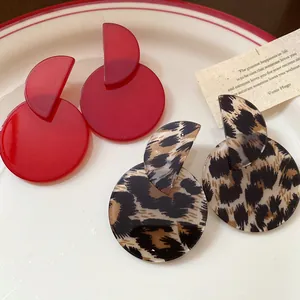 Close-up of retro red and leopard print acrylic drop earrings on a vintage white plate