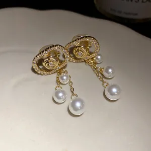 Close-up detail of luxury 18k gold plated zircon oval earrings with white pearl tassels