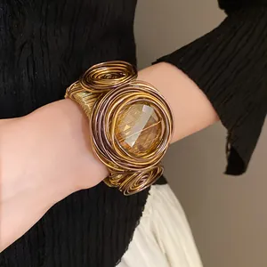 Dettaglio di un bracciale a polsino boho intrecciato con grande cristallo ambrato.