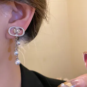 Detailed view of 18k gold plated zircon oval clip-on earrings with pearl tassels