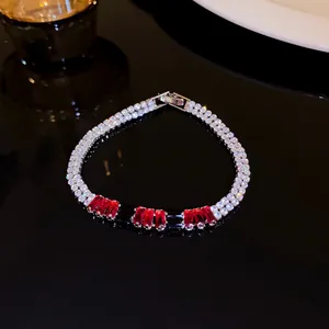 Close-up detail of silver-tone bracelet with rows of clear zircons and red baguette crystals.