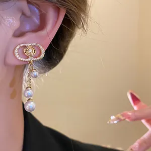 Detailed view of 18k gold plated oval ear clip with zircon and elegant pearl tassels