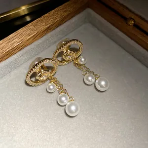 Close-up of 18k gold plated zircon oval earrings with pearl tassels in jewelry box