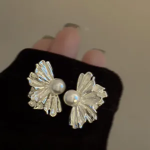 Vista dettagliata di orecchini a fiore pieghettati in argento con perle eleganti