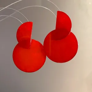 Close-up detail of vibrant red geometric resin drop earrings with subtle marble texture
