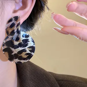 Detailed view of vintage leopard print asymmetric round earrings on model's ear