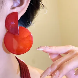 Detail view of retro asymmetric marbled red round drop earrings on a model's ear