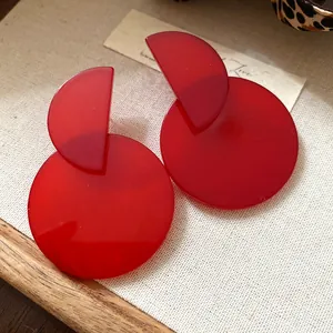 Close-up detail of retro red acrylic geometric drop earrings on linen background
