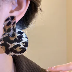 Detail of retro leopard print asymmetric round drop earrings on model ear