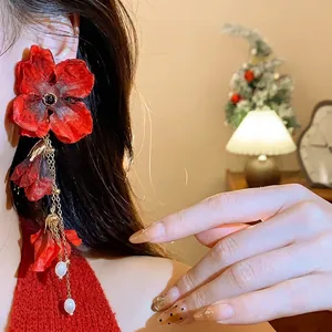 Elegant red fabric flower earrings with long tassels and pearls worn by a model.
