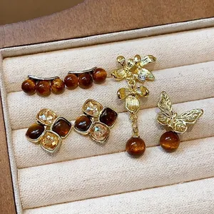 Elegant vintage asymmetric earrings set with amber resin flowers and butterfly gold charms