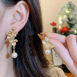 Elegant asymmetric gold flower and butterfly earrings with shimmering resin bead drops