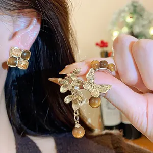 Detailed view of asymmetric vintage earrings with gold butterfly and brown beads