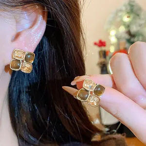 Detailed close-up of elegant vintage amber resin and crystal four-petal flower stud earrings