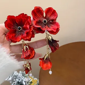 Detailed view of elegant red fabric flower earrings with gold tassels and pearls