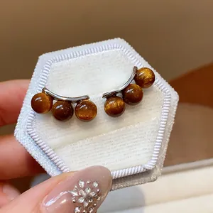 Close-up of retro silver needle earrings with shimmering brown resin beads.