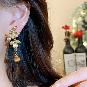 Elegant close-up of a gold resin flower earring featuring a dangling amber bead detail